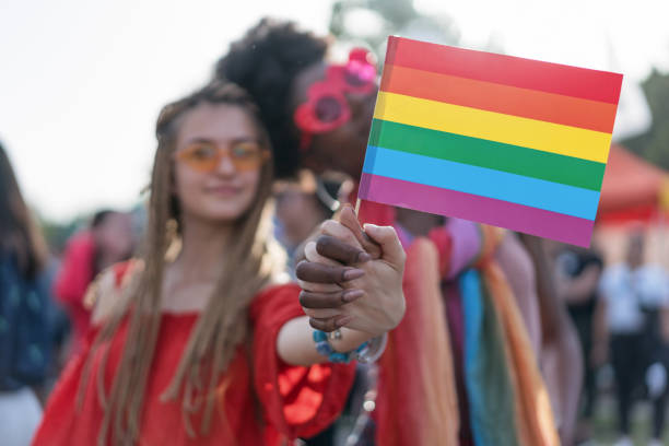 istock Female couple holding together rainbow pride flag 1205354850