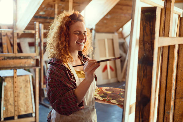istock Artist working in studio on her painting smiling 1205355059