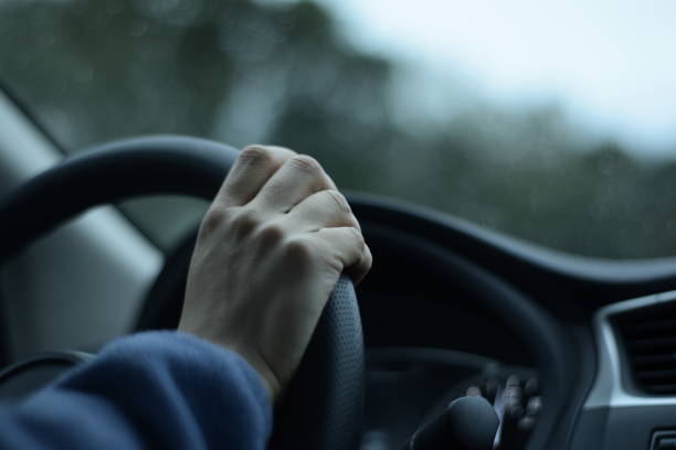 istock Low Angle View Of Hand On A Steering Wheel While Driving A Car Against Defoused Background 1205361228