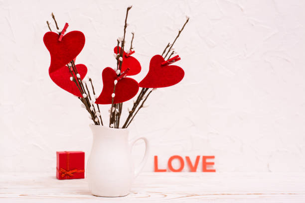 istock Valentine's Day. Red hearts made of felt on willow branches in a white jug on the table, a gift and the word 