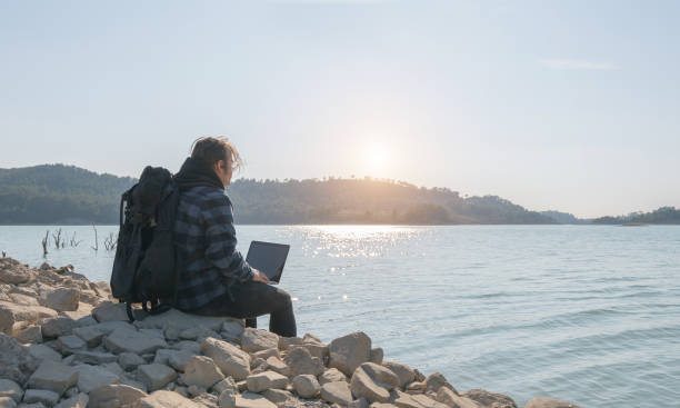 istock Young hiker man using laptop by the lake 1205361654