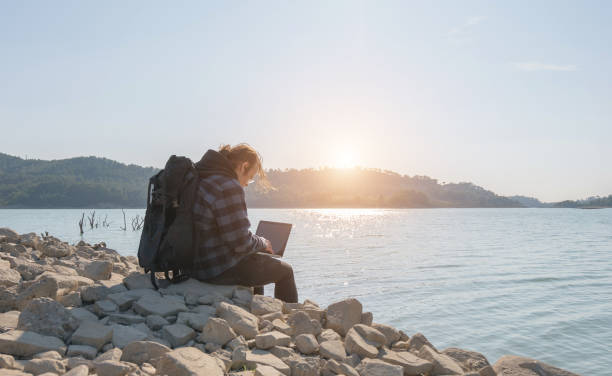 istock Young hiker man using laptop by the lake 1205361710