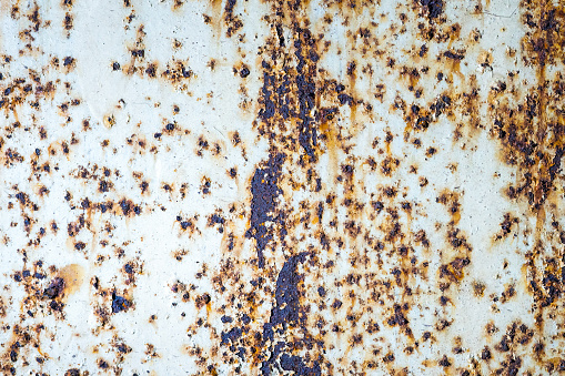 Rusty metal wall with cracked white paint.