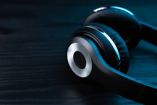 istock Black headphone on dark wooden background. Stylish wireless headset in neon light. 1205364393