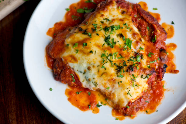 chicken parmigiana traditional italian comfort dish. chicken breast covered in breadcrumbs lightly fried, topped with homemade marinara, melted mozzarella, parmigiana provolone and italian parsley. - parmesan cheese imagens e fotografias de stock