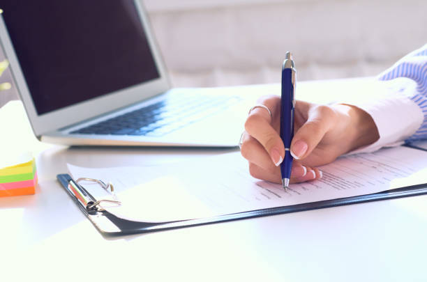 istock Businesswoman sitting at office desk signing a contract or making notes. 1205366085