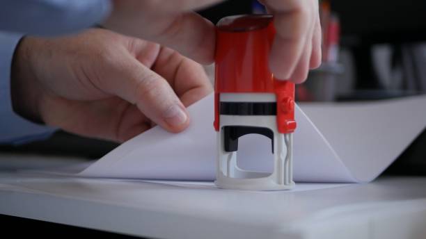 istock Businessman Hand Stamping Papers and Documents Using a Rubber Stamp, Office Job with Files and Contracts 1205367488