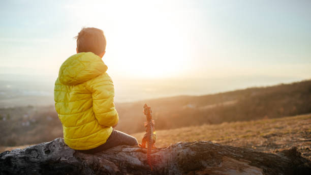 Photo of a little boy enjoying the sunset from the top hill