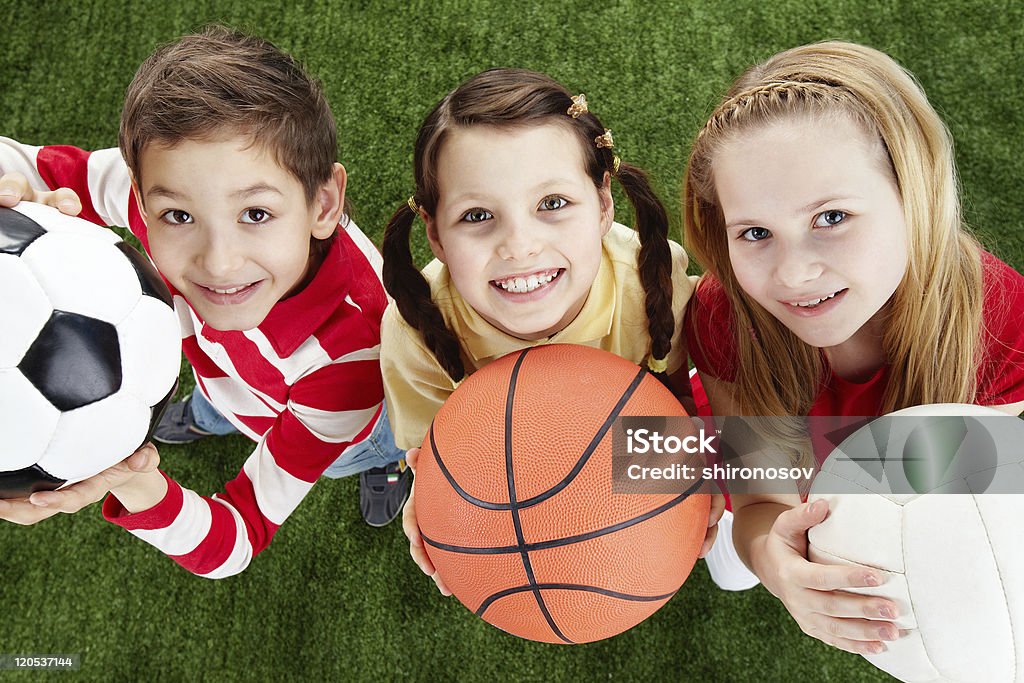 Happy friends Image of happy friends on the grass with balls looking at camera Child Stock Photo