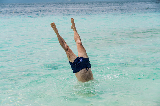 Young men handstand in turquoise sea