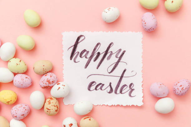 istock Inscription HAPPY EASTER letters candy chocolate eggs and jellybean sweets isolated on trendy pastel pink background. Simple minimalism flat lay top view copy space 1205371787