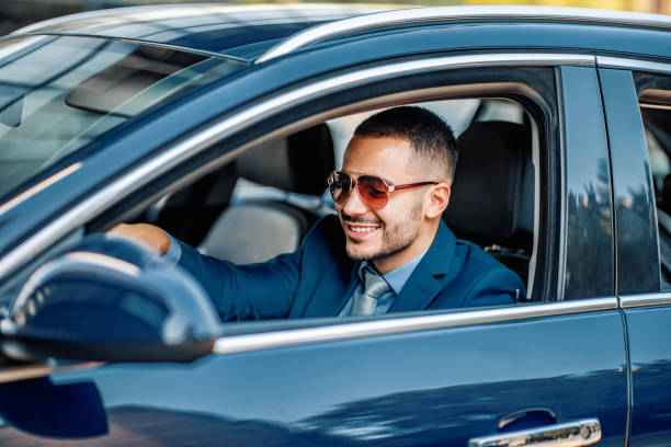istock Young successful businessman driving his new car 1205372884