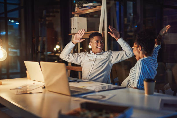 Nothing feels better than beating a deadline Shot of a young businessman and businesswoman giving each other a high five during a late night meeting passion stock pictures, royalty-free photos & images