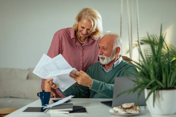 istock Senior couple using laptop while sitting at the table in the living room and going through paperwork 1205376050