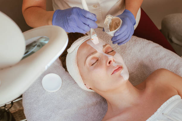 istock A beautician applying a face mask on a female client. 1205377328