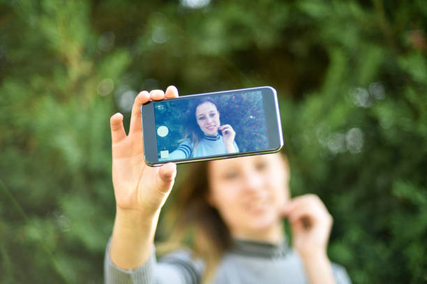 istock Young woman is taking a selfie by mobile phone. Green background. 1205380376