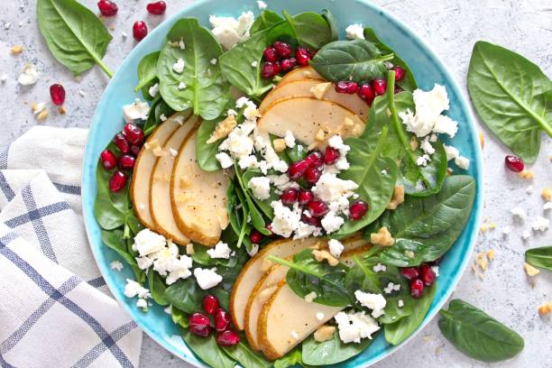Fresh salad with baby spinach, pear, feta cheese, nuts and pomegranate. stock photo