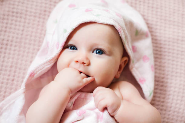 authentiek portret van 4 maanden babymeisje dat in handdoek na bad wordt verpakt. - bad fotos stockfoto's en -beelden