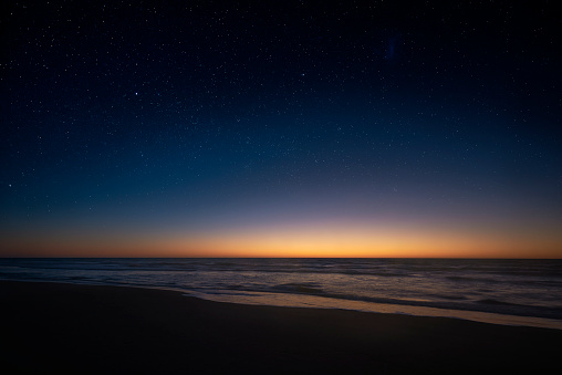 Amazing panoramic view of the Milky Way vanishing above the coast line of the Atlantic Ocean, as the sun rises over the horizon in the Southern hemisphere. Beautiful starry sunrise over the sea.
