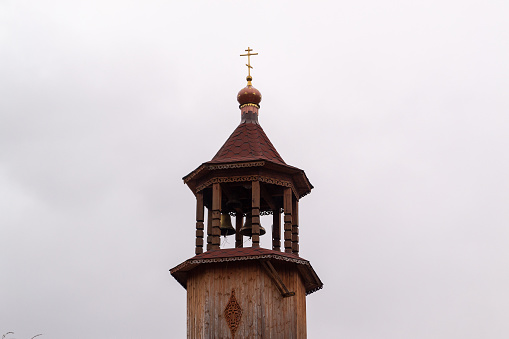 The bell tower of an Orthodox church on a background of cloudy sky.