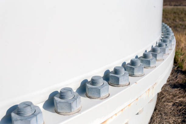 Lug nuts on a wind turbine spinning for renewable electricity production with blue sky in the background.