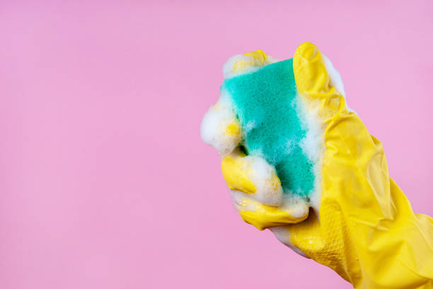 istock Gloved hand holds a foam sponge on a pink background copy space 1205398328