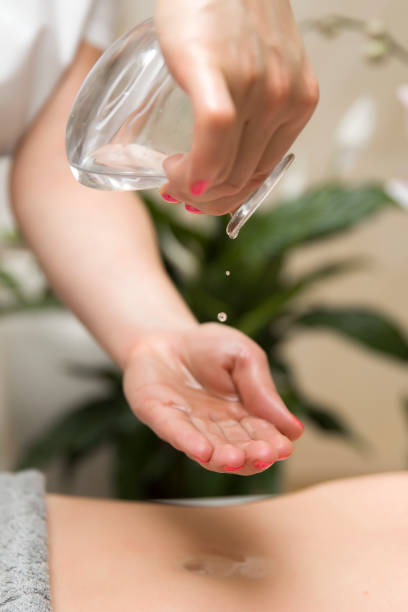 istock Masseuse puts massage oil in her hand 1205399370
