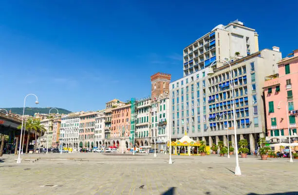 Photo of Row of colorful buildings and Tower Torre dei Morchi on Piazza Caricamento square near harbor in historical centre of old european city Genoa Genova with blue sky background, Liguria, Italy