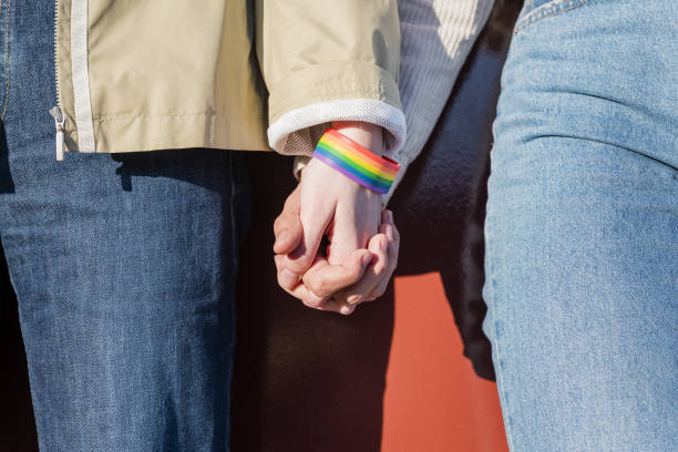 istock linked hands of two women with a rainbow bracelet 1205401292