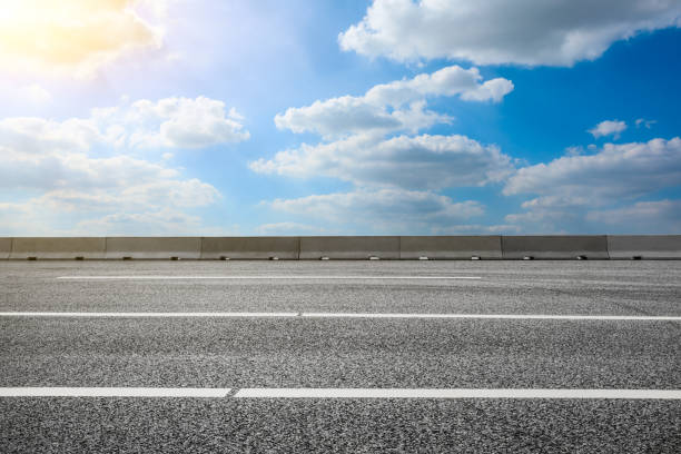 istock Asphalt road and blue sky with white clouds in summer 1205413071
