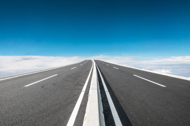 istock Asphalt road and blue sky with white clouds in summer 1205414006