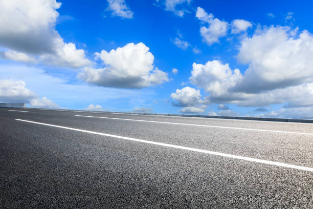 istock Asphalt road and blue sky with white clouds in summer 1205414044