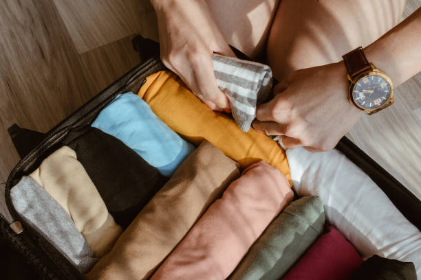 feche de casa de turista abra o rolo de mala e embalar panos coloridos para viajar. - rolling - fotografias e filmes do acervo