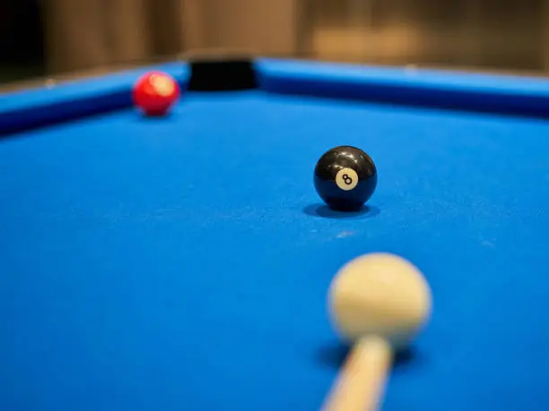 Pool table with billiard balls focused on the eight-ball. Final ball: winning the game when shooting the eight ball in the pool pocket.