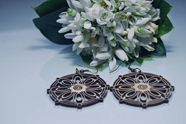 Wooden earrings with bouquet of snowdrops Elegant round wooden earrings on the table together with a white delicate bouquet of snowdrops hoops wedding stock pictures, royalty-free photos & images