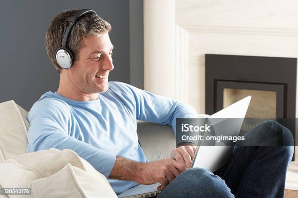 Man Using Laptop Wearing Headphones Relaxing Sitting On Sofa Stock Photo - Download Image Now