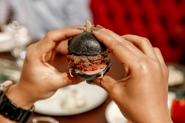 Eating mini burger for appetizer Close up young women eating mini burger for snack in tapas event spanish hamburger stock pictures, royalty-free photos & images
