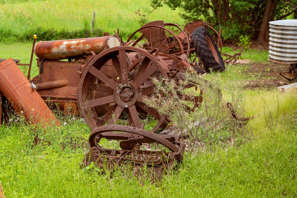 Old rusted farm machinery from a bygone era lying in an overgrown field