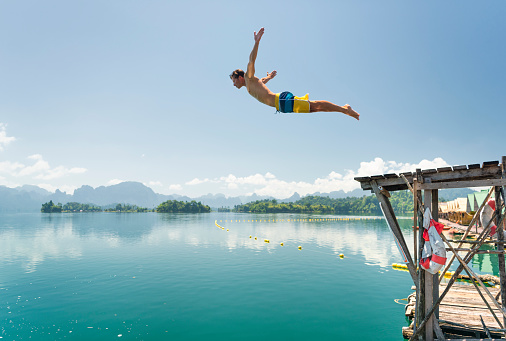 Athletic tourist jumping in the clear Lake Ratchaprapha, Khao Sok Nationalpark, Thailand. Nikon D810. Converted from RAW.