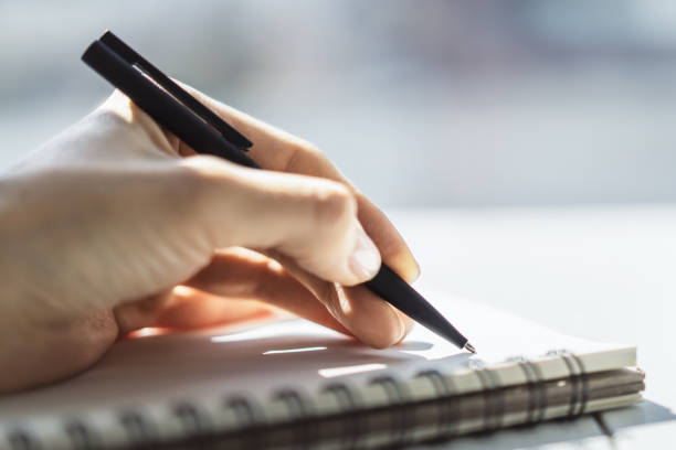 istock Woman writing in notepad. Close up. Focused on a hand with pen 1205439540