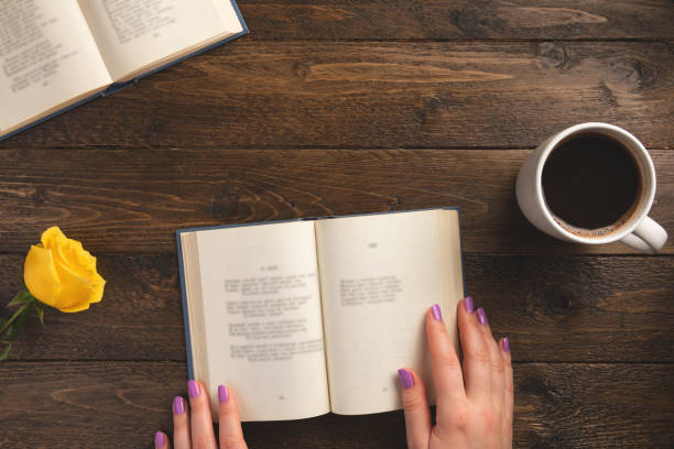 istock Female hands and opened book, on wooden background. Flat lay, top view, copy space. 1205443366