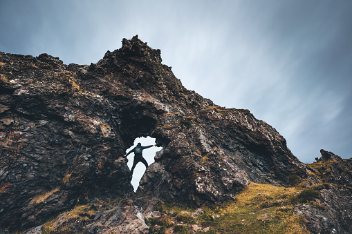 Man looking through the hole in rock formation near Djupalonssandur beach (Snaefellsjokull Peninsula) in Iceland.