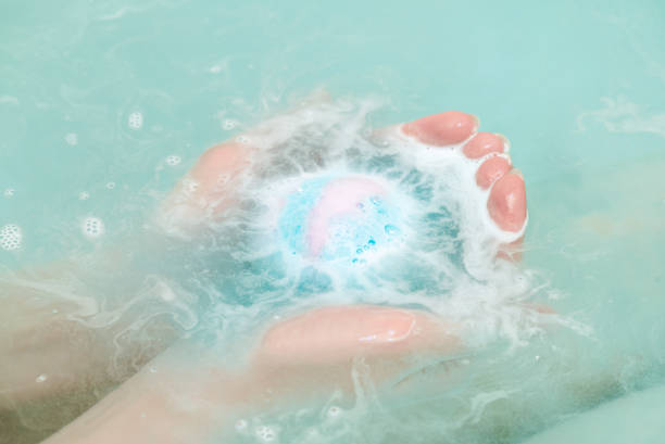 Bath bomb. Bath ball in female hands close up in the water. bath salt photos stock pictures, royalty-free photos & images