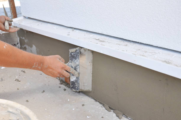 A contractor is plastering, repairing stucco house foundation after styrofoam insulation. A contractor is plastering, repairing stucco house foundation after styrofoam insulation. waterproof photos stock pictures, royalty-free photos & images