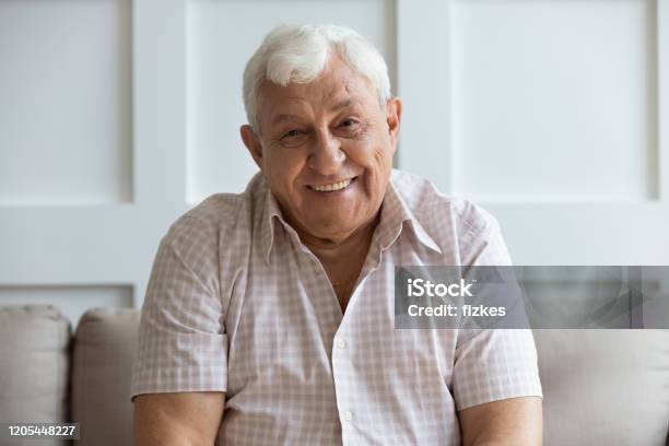 Headshot Portrait Of Smiling Mature Man Relaxing On Sofa Stock Photo - Download Image Now