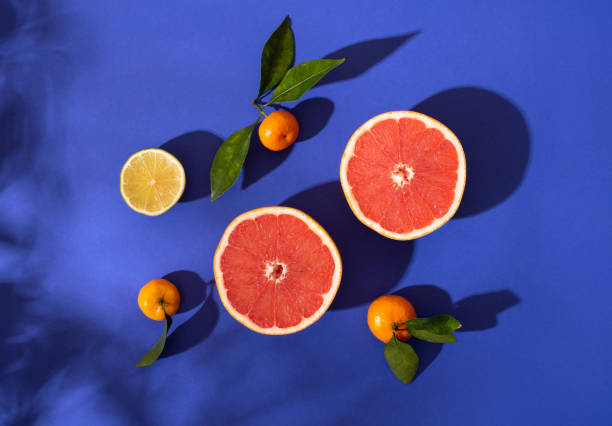 Composition with citrus fruits on a bright blue background. Bright light, contrasting shadows.