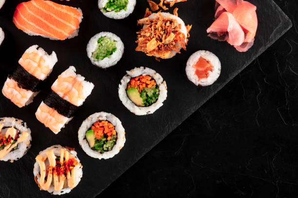 istock Large sushi set, shot from the top on a black background with a place for text. A flatlay of various maki, nigiri and rolls 1205450516