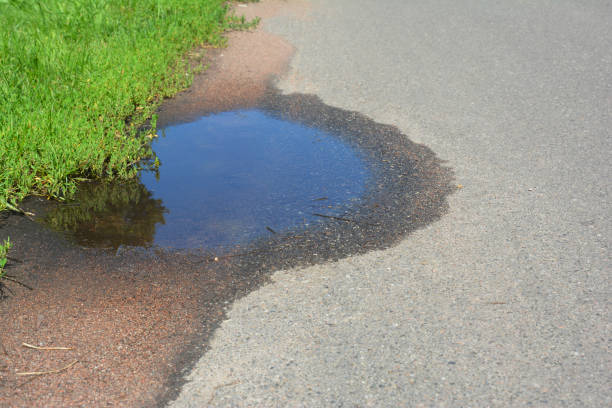 istock Asphalt road in puddles. Ppothole image of a broken cracked asphalt pavement. 1205450558