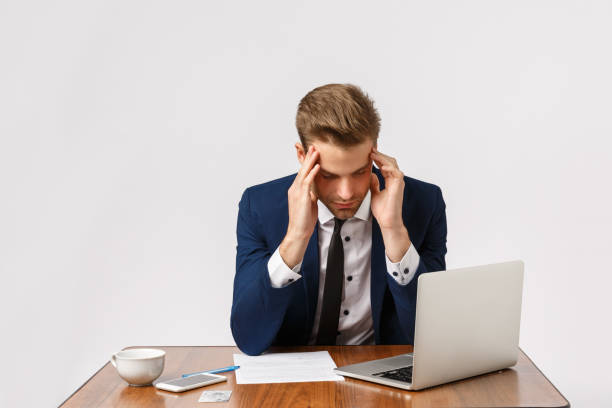 istock Failure, fatigue and depression concept. Man having bad day, feeling let down, losing important case in court, sitting office table with laptop and documents, touching temples, have headache 1205452074