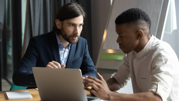 istock Businessman mentor training African American intern, giving instructions 1205454364